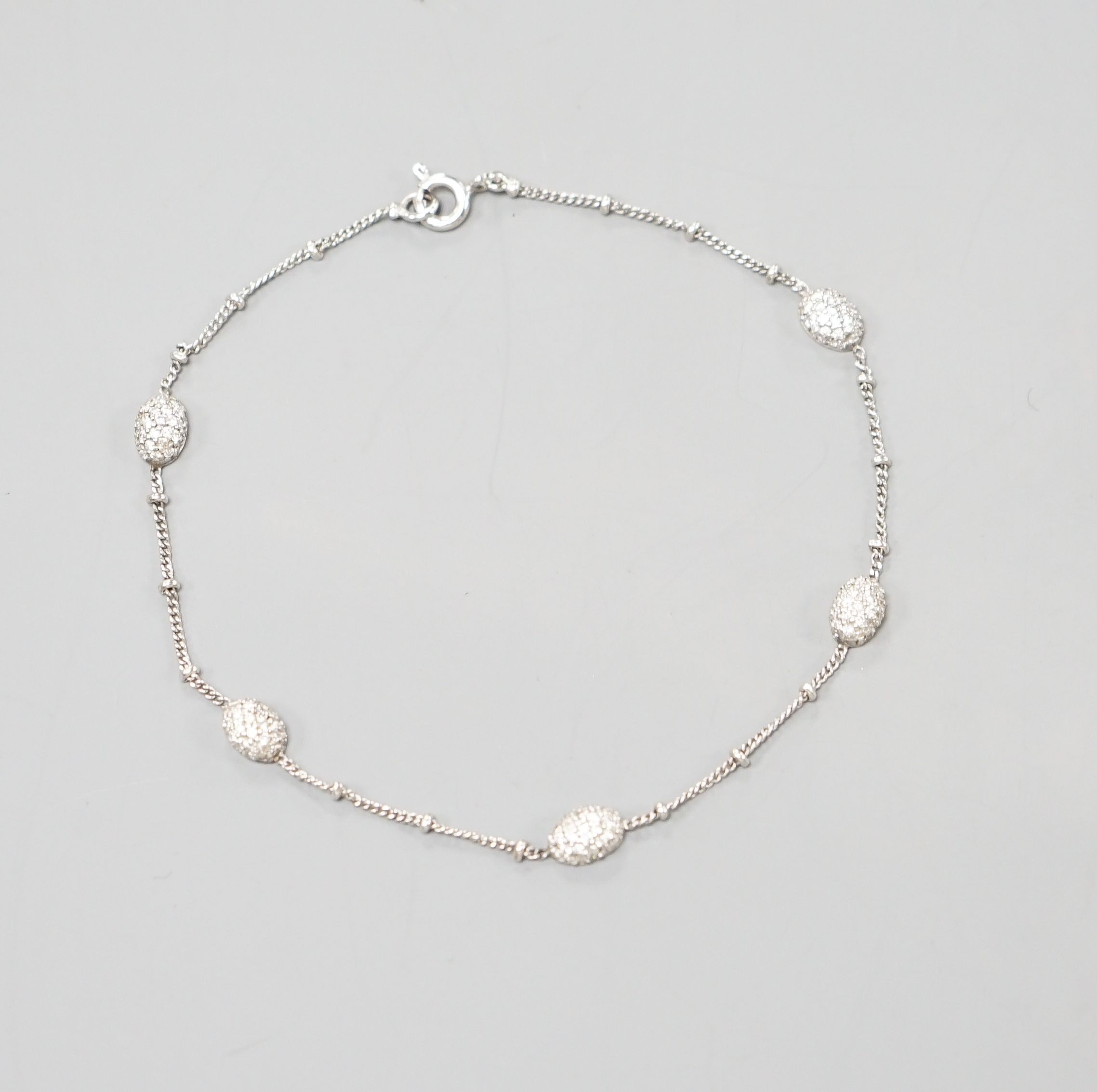 A modern 750 white metal and diamond chip set demi lune link bracelet, 19cm